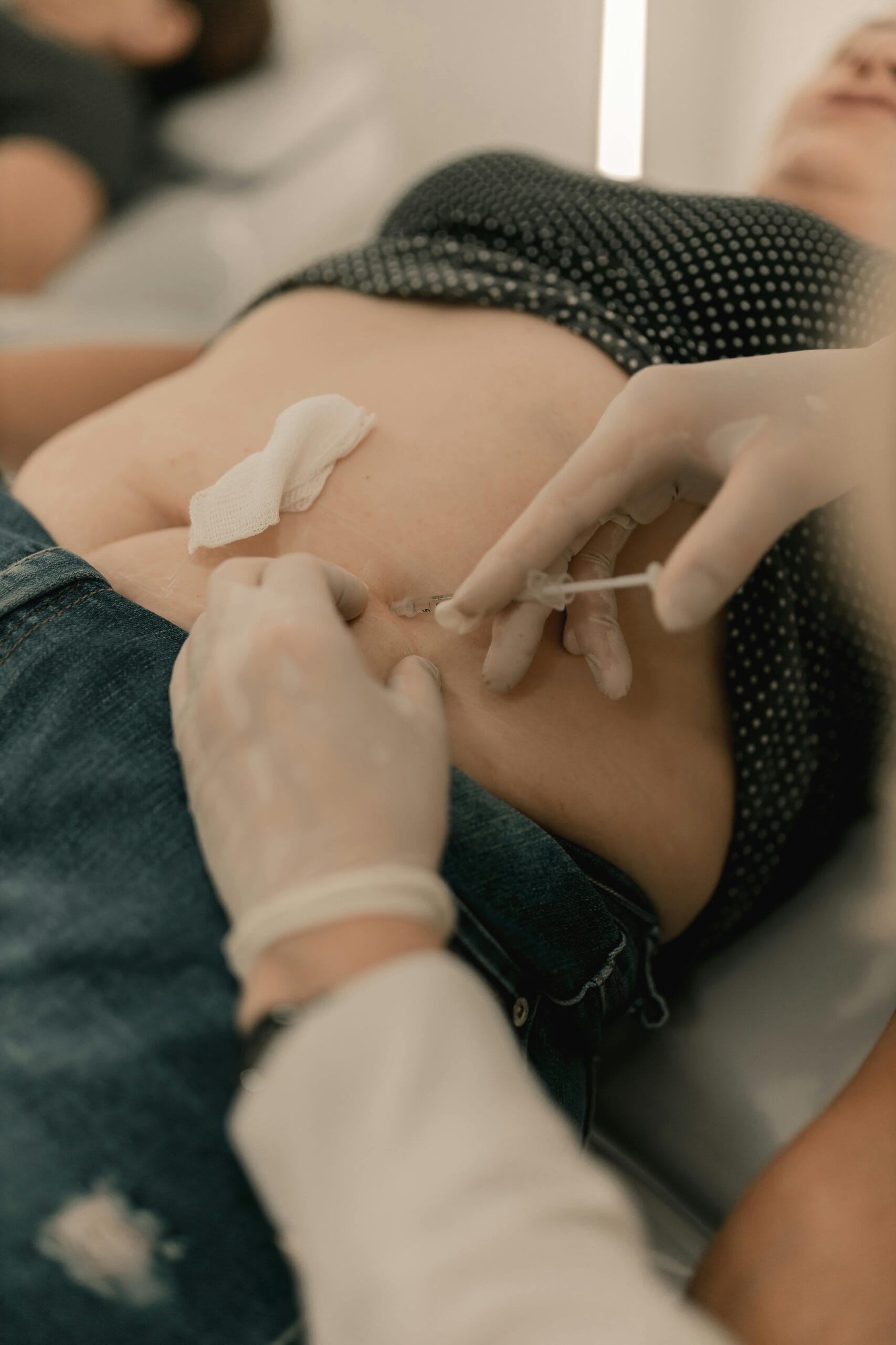 Médico aplicando inyección subcutánea de enzimas recombinantes en zona abdominal de paciente en consultorio estético